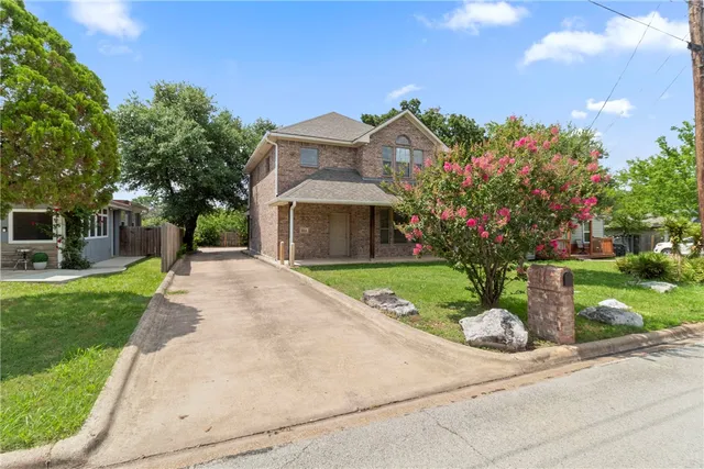 a front view of a house with a yard and potted plants