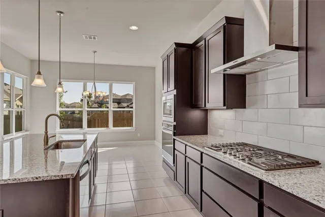 a kitchen with granite countertop a stove a sink and a refrigerator