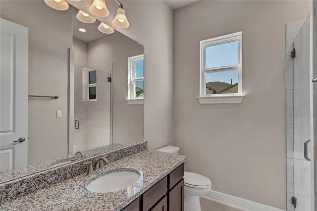 a bathroom with a granite countertop sink a toilet and a mirror
