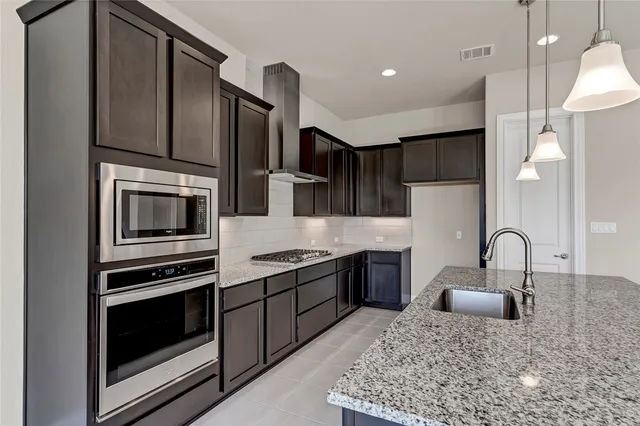 a kitchen with stainless steel appliances kitchen island granite countertop a stove a sink and a microwave