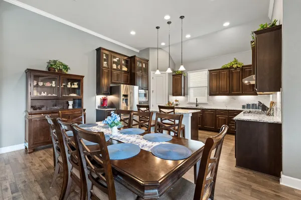 a dining room with stainless steel appliances kitchen island granite countertop a dining table chairs and a oven