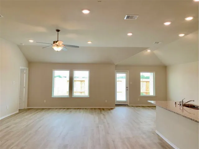 a view of an empty room with window and wooden floor