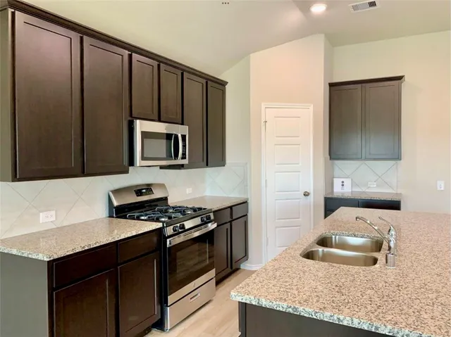 a kitchen with granite countertop wooden cabinets and a stove top oven