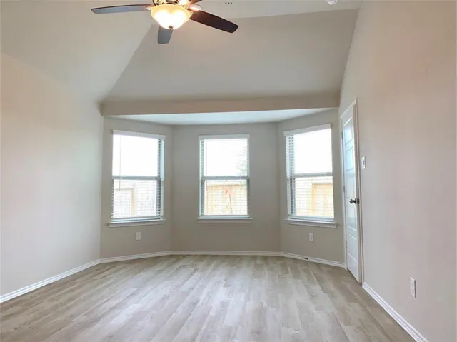 an empty room with chandelier fan and windows