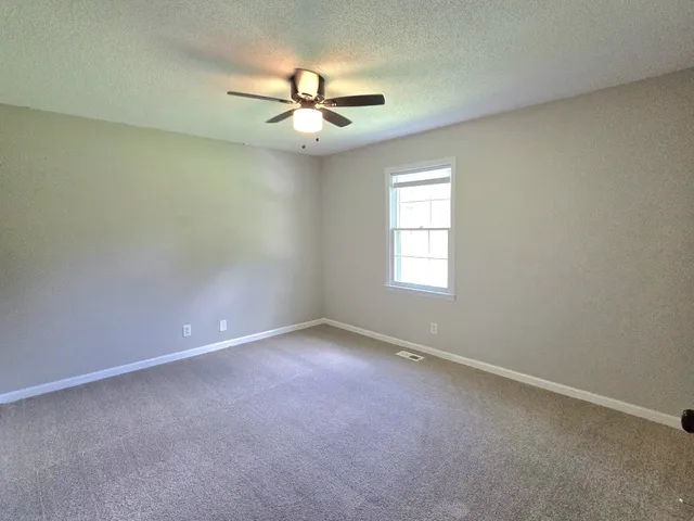 an empty room with a window and a fan
