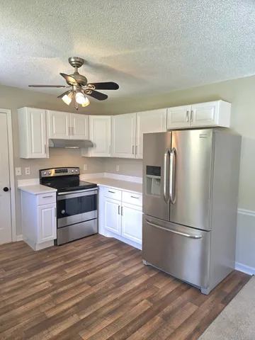 a kitchen with granite countertop stainless steel appliances a refrigerator cabinets and wooden floor