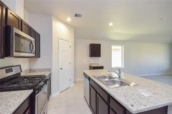 a kitchen with granite countertop stainless steel appliances a sink stove and cabinets