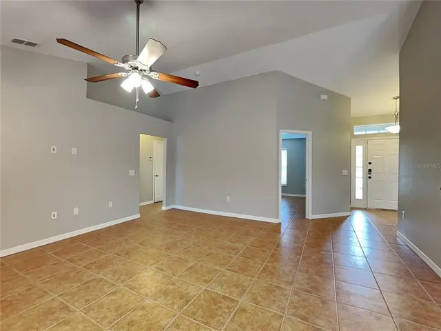 a view of an empty room with a chandelier fan