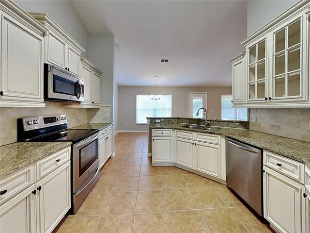 a kitchen with stainless steel appliances granite countertop a stove top oven a sink dishwasher and white cabinets with wooden floor