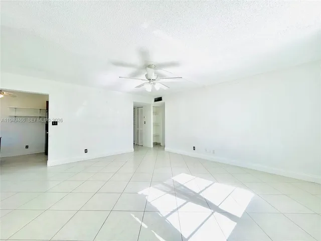 an empty room with white walls and chandelier fan