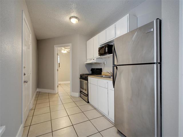 605 Elmwood Place, Unit B Austin, TX 78705 - Photo 2 of 10 a kitchen with a refrigerator a microwave and cabinets