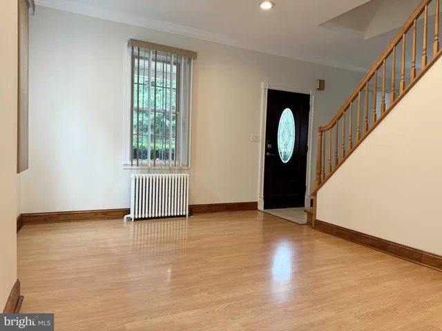 a view of an empty room with wooden floor and window