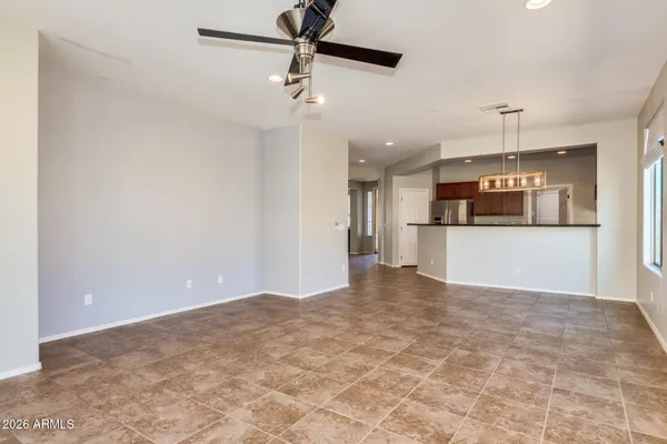 an empty room with chandelier fan and windows