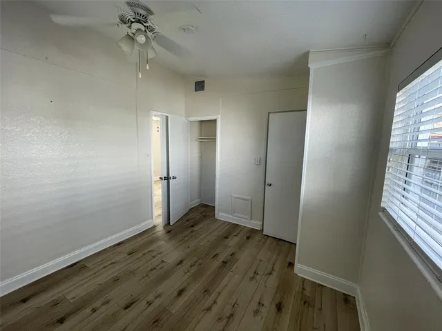 an empty room with wooden floor and closet area