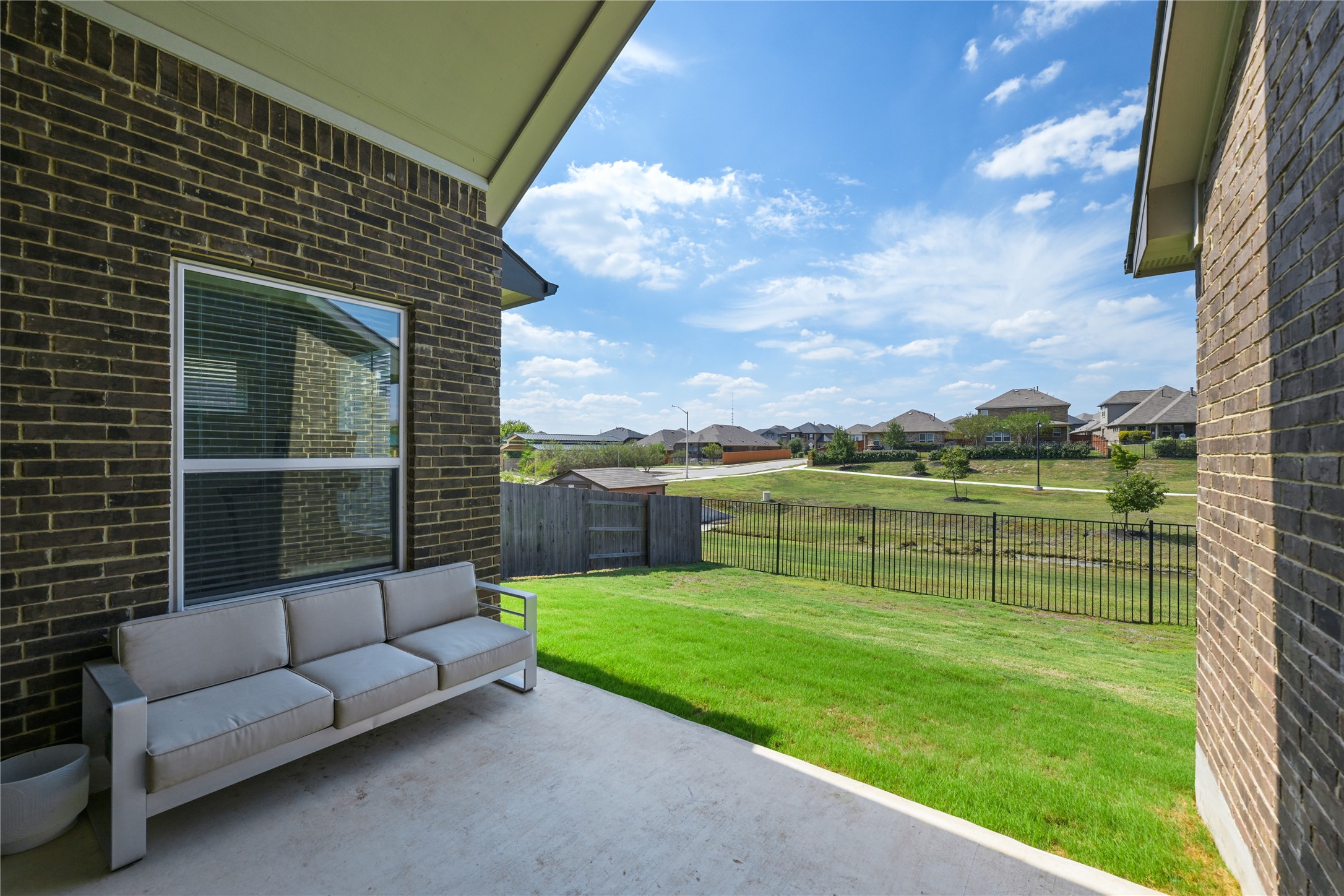 238 Wild Pecan Loop Buda, TX 78610 - Photo 26 of 31 A covered back patio overlooks a grassy yard framed by wrought iron fencing.