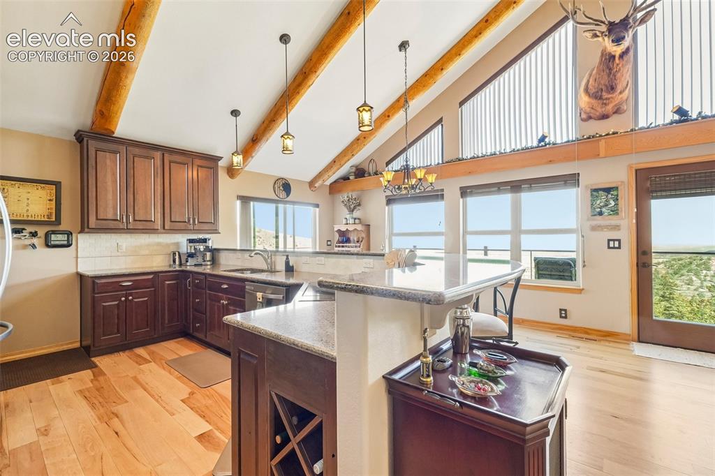 858 Oak Ridge Road Manitou Springs, CO 80829 - Photo 19 of 50 Open concept kitchen with quartz counter tops, matching stainless appliances, rustic cherry cabinetry, a breakfast bar and a wine rack all surrounded by solid hickory flooring