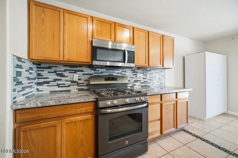 7873 Welsh Drive Reno, NV 89506 - Photo 10 of 34 a kitchen with stainless steel appliances granite countertop a stove a sink and a microwave