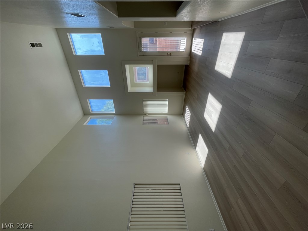 Towering ceilings and multi-level windows define this airy, light-filled living space featuring modern plank flooring.