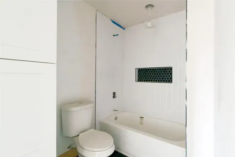 a white toilet sitting next to a bath tub