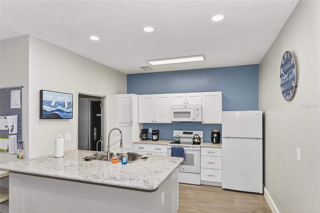 4160 Fruitville Road, Unit 11 Sarasota, FL 34232 - Photo 52 of 63 a kitchen with granite countertop a refrigerator a stove a sink and white cabinets with wooden floor