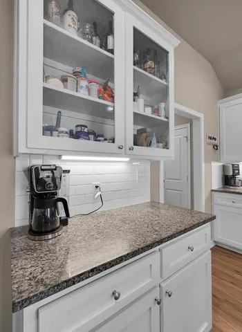 a kitchen with granite countertop white cabinets and a sink