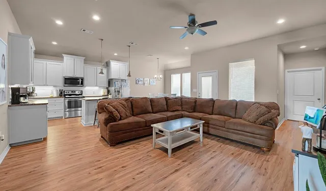 a living room with furniture kitchen and a wooden floor