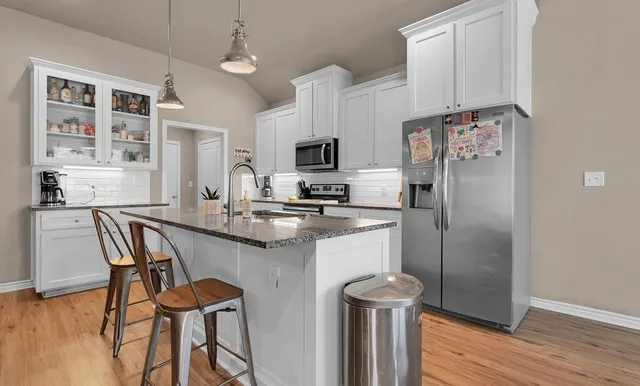 a kitchen with stainless steel appliances granite countertop a dining table chairs refrigerator and sink