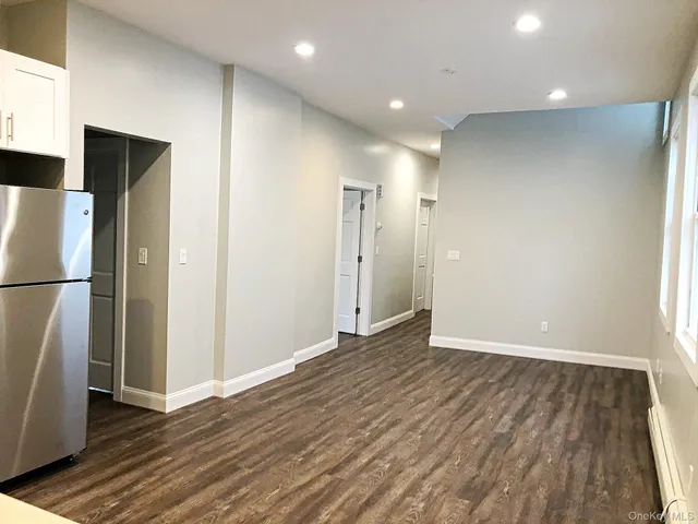 a view of empty room with wooden floor and electronic appliances