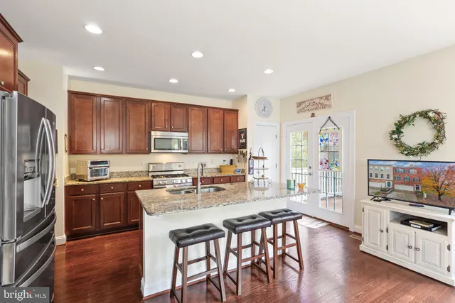 a kitchen with stainless steel appliances granite countertop a stove top oven a refrigerator a sink and dishwasher with wooden floor