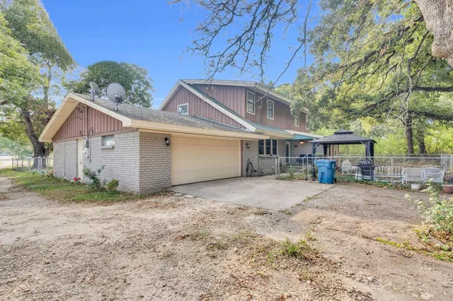 a view of a house with a yard and large tree