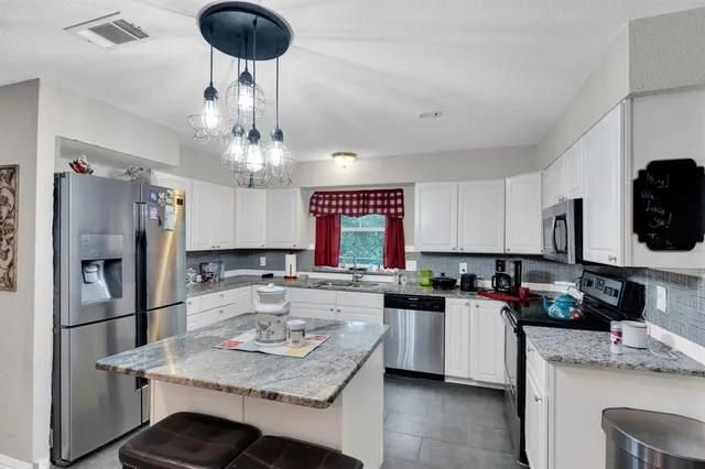 a kitchen with stainless steel appliances granite countertop a stove top oven a refrigerator a sink and dishwasher