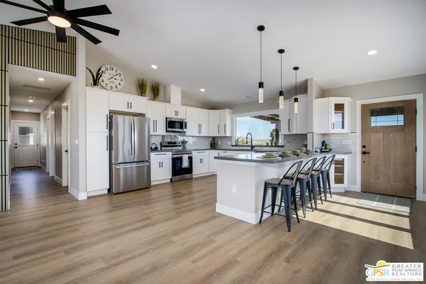 a kitchen with stainless steel appliances granite countertop a refrigerator a stove top oven a sink dishwasher and a dining table with wooden floor
