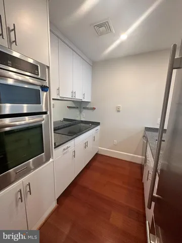 a kitchen with granite countertop white cabinets and white appliances