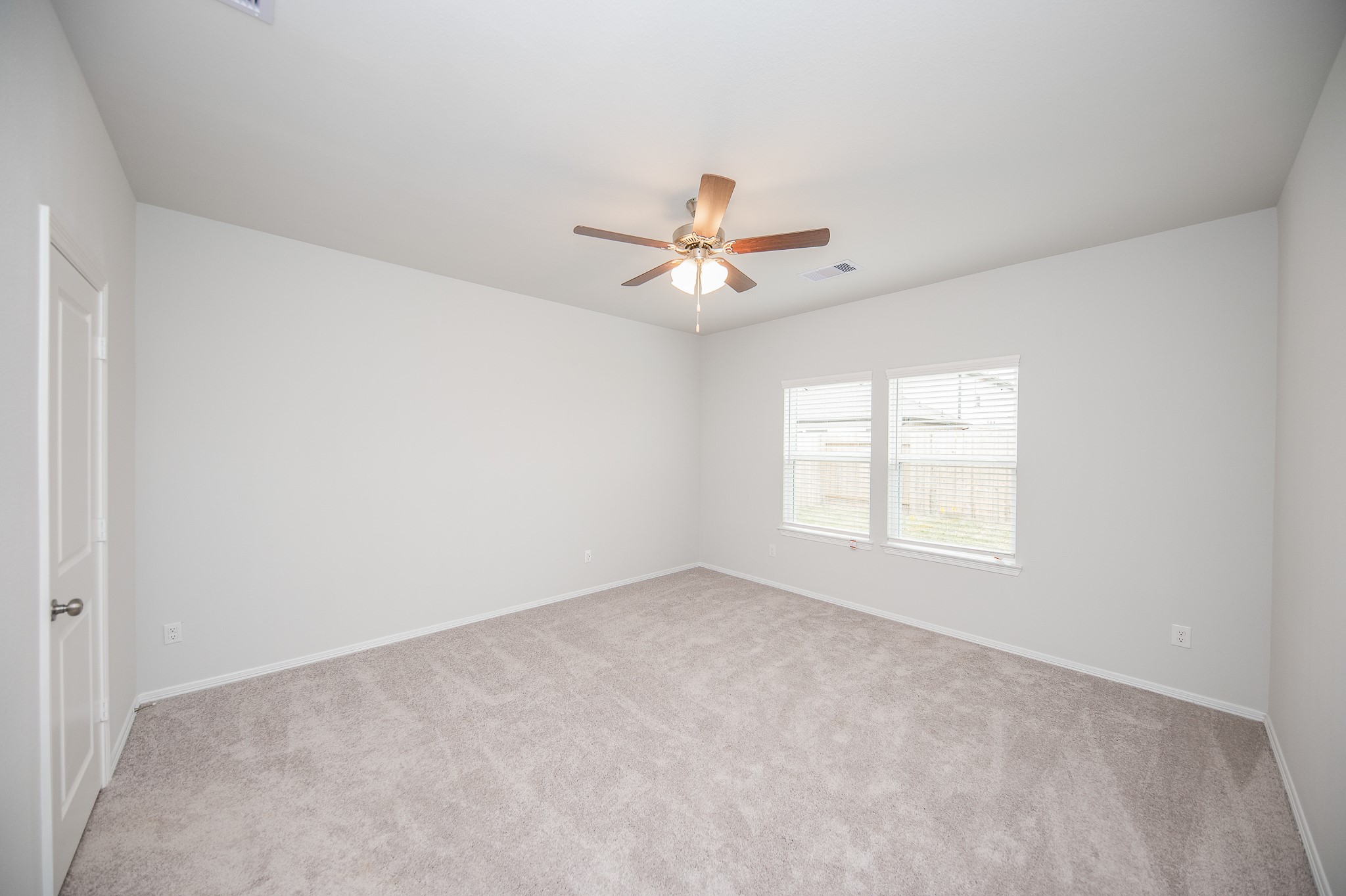 23302 Spring Genesis Lane Katy, TX 77493 - Photo 21 of 32 This room features soft carpet flooring, neutral walls, and a ceiling fan. It has two large windows allowing natural light and a door for easy access. Perfect for a bedroom or office space.