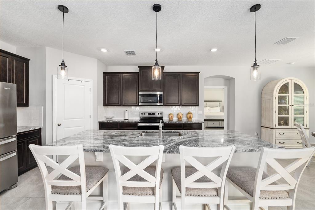 5912 Southwest 46th Drive Gainesville, FL 32608 - Photo 23 of 74 a kitchen with stainless steel appliances kitchen island granite countertop a dining table chairs and sink