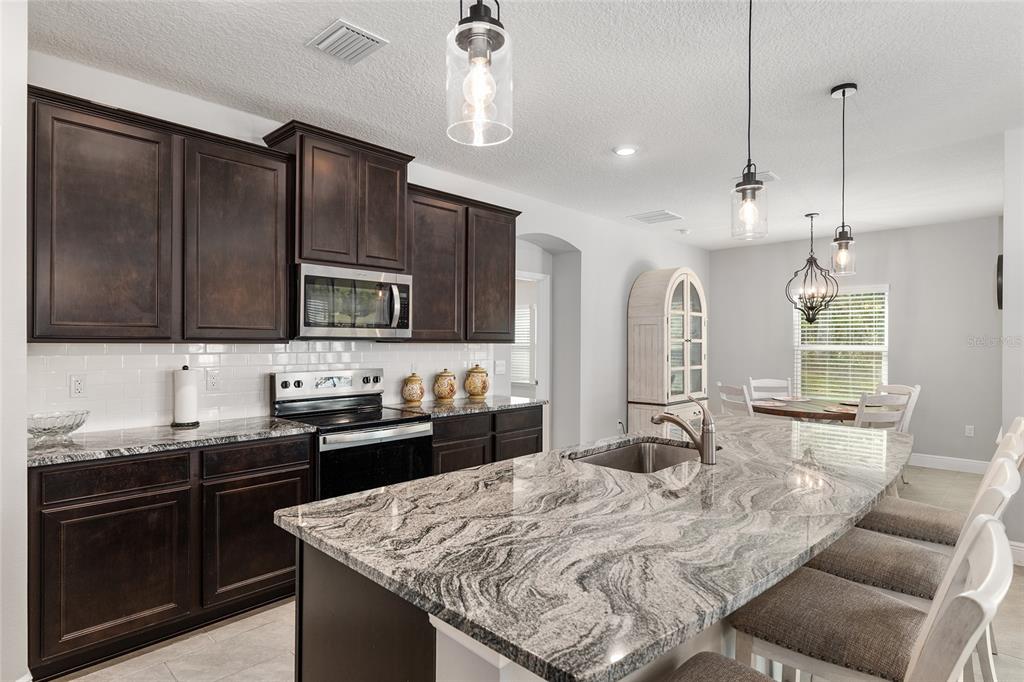 5912 Southwest 46th Drive Gainesville, FL 32608 - Photo 25 of 74 a kitchen with kitchen island granite countertop a sink appliances and cabinets