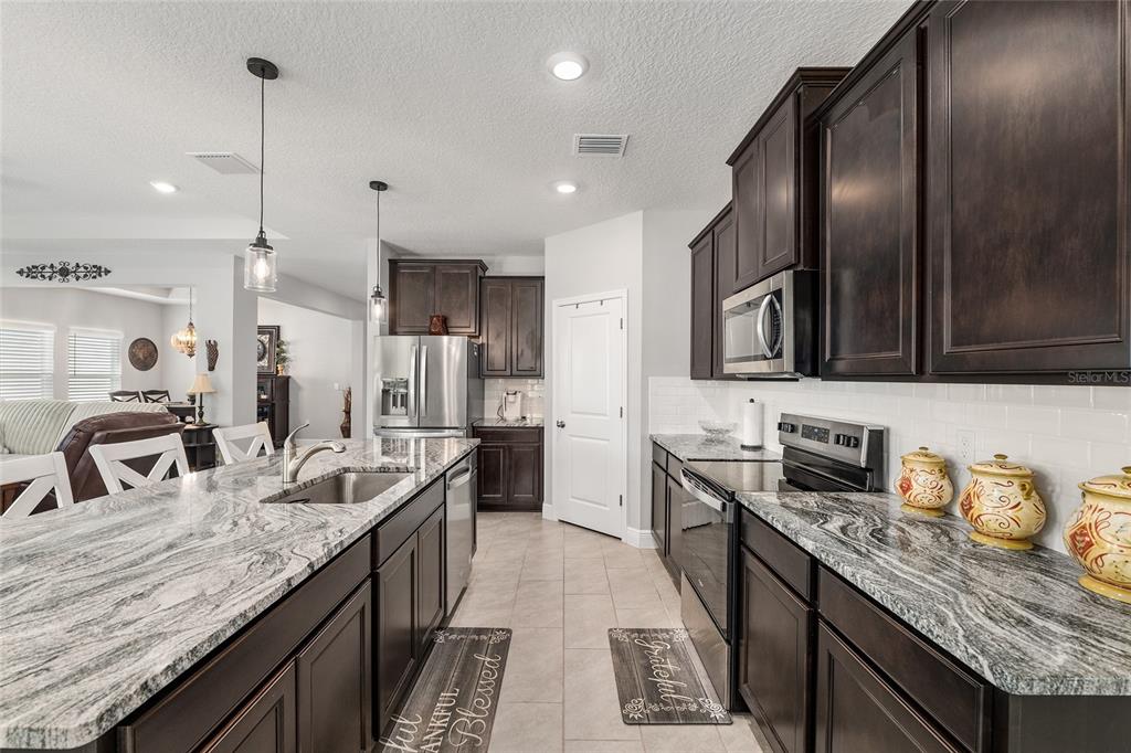 5912 Southwest 46th Drive Gainesville, FL 32608 - Photo 28 of 74 a kitchen with granite countertop stainless steel appliances and wooden cabinets