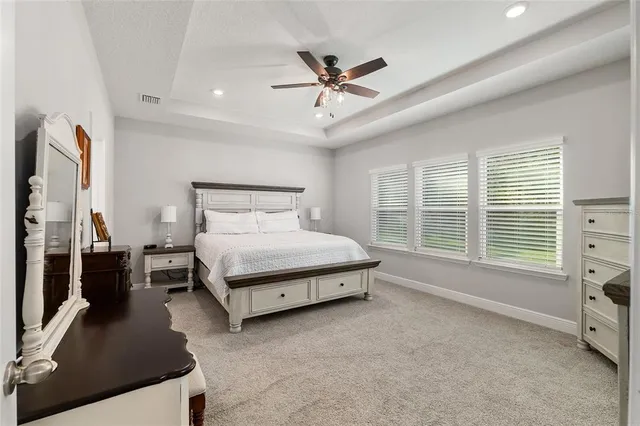 a bedroom with a bed a dresser and a chandelier