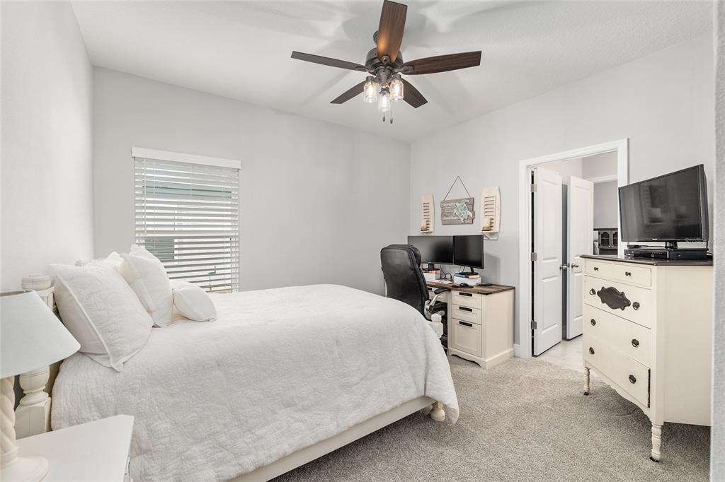 5912 Southwest 46th Drive Gainesville, FL 32608 - Photo 44 of 74 a bedroom with furniture a flat screen tv and a ceiling fan