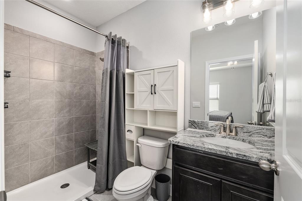 5912 Southwest 46th Drive Gainesville, FL 32608 - Photo 58 of 74 a bathroom with a granite countertop sink a toilet and shower