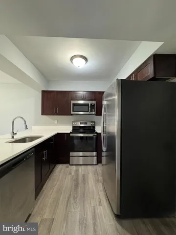 a kitchen with stainless steel appliances a refrigerator a sink dishwasher stove and oven with wooden floor