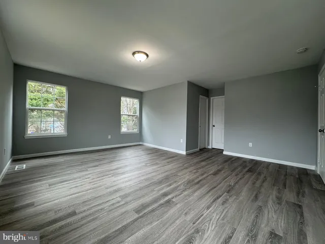 an empty room with wooden floor and window