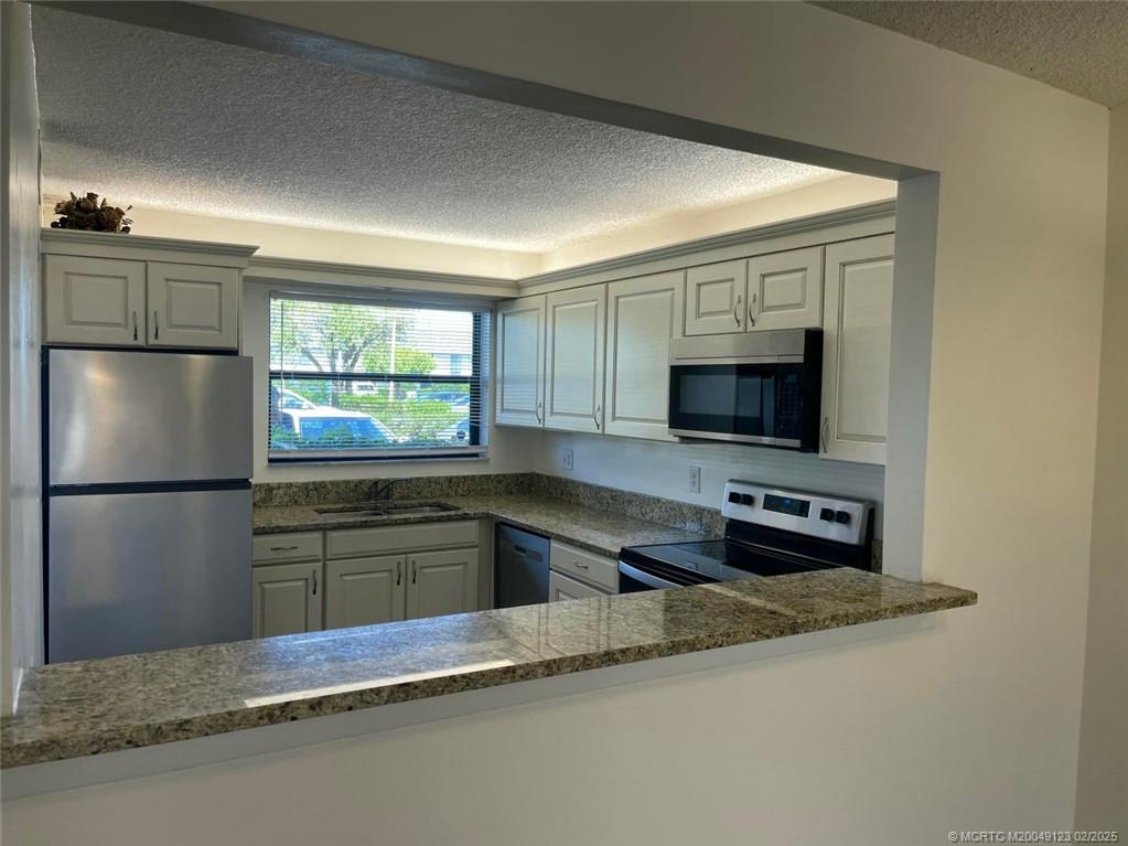 1270 Southeast Parkview Place, Unit B3 Stuart, FL 34994 - Photo 10 of 40 a kitchen with stainless steel appliances a refrigerator sink and microwave