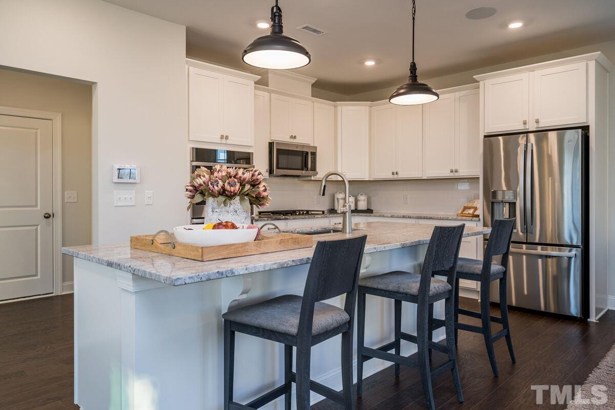 2201 Goudy Drive Raleigh, NC 27615 - Photo 14 of 24 a kitchen with stainless steel appliances a dining table chairs refrigerator and microwave