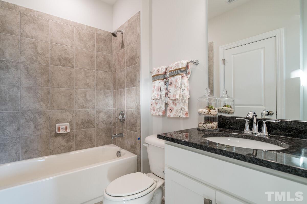 2201 Goudy Drive Raleigh, NC 27615 - Photo 7 of 24 a bathroom with a granite countertop bathtub shower sink vanity mirror and toilet