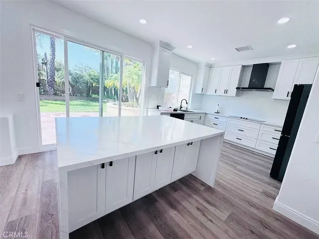 a large white kitchen with wooden floors and white stainless steel appliances