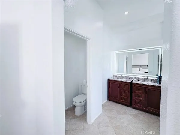 a spacious bathroom with a granite countertop sink a toilet and a mirror
