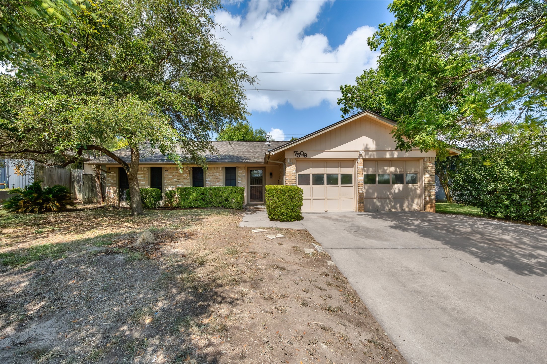 7506 Glenhill Road Austin, TX 78752 - Photo 1 of 20 A classic ranch-style home features an attached garage and a neatly manicured front hedge, framed by mature trees.