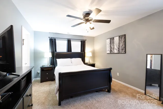 a bedroom with a bed and a flat tv screen on dresser