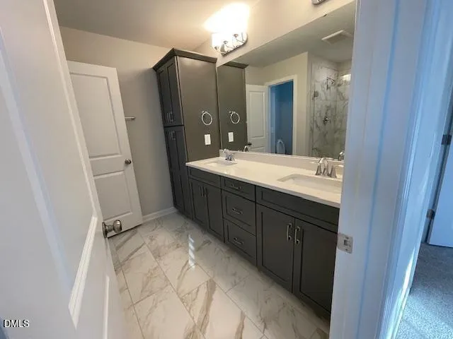 a spacious bathroom with a double vanity sink a mirror and a shower